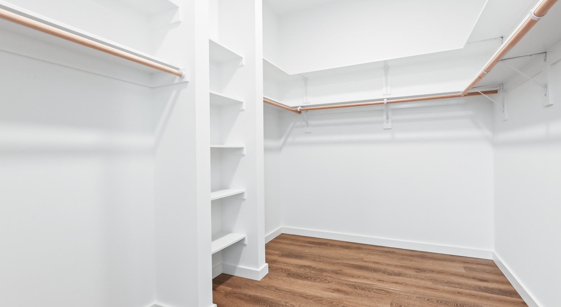 a closet with white walls and wood floors