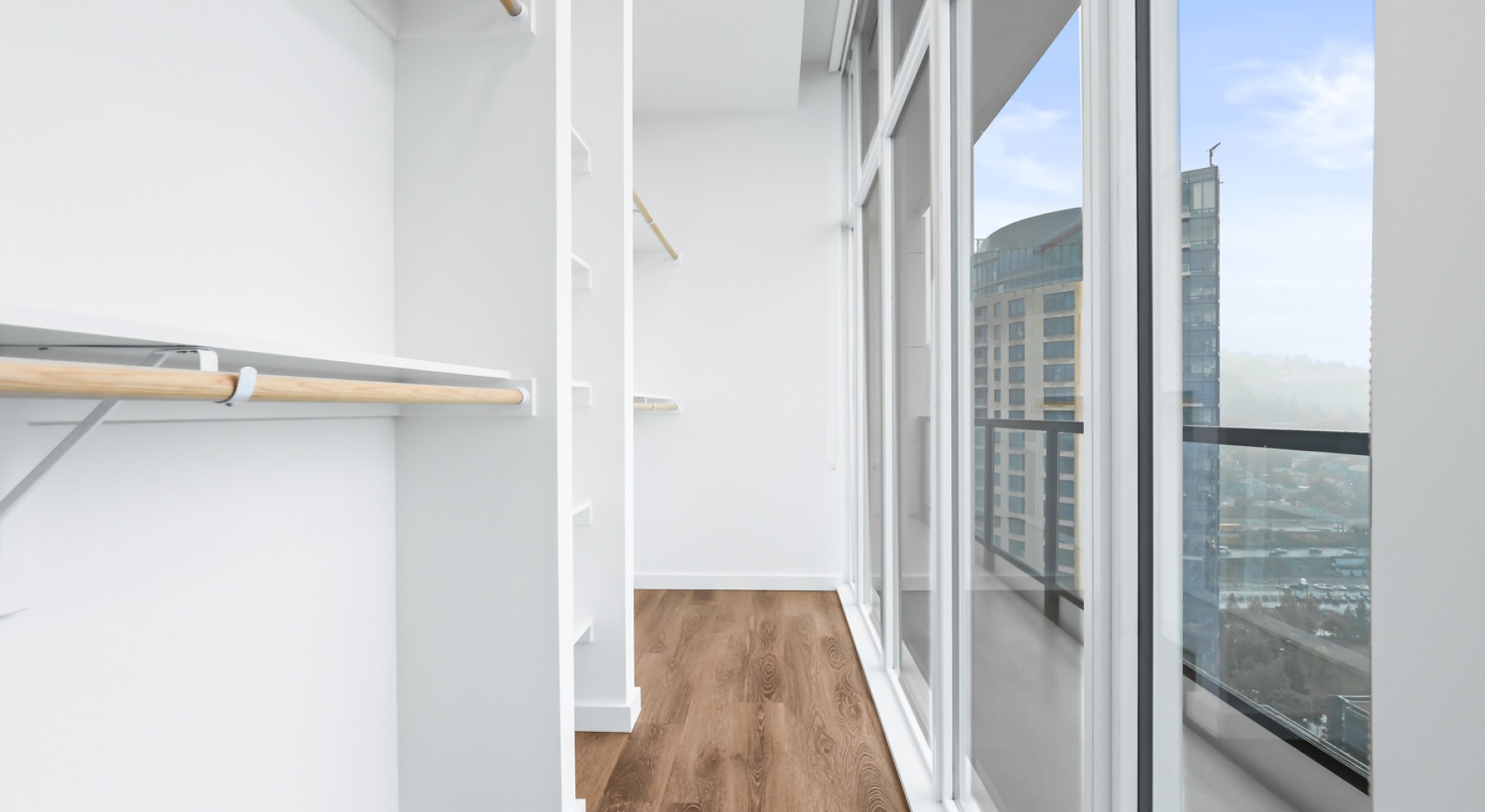 a closet with white walls and wood floors