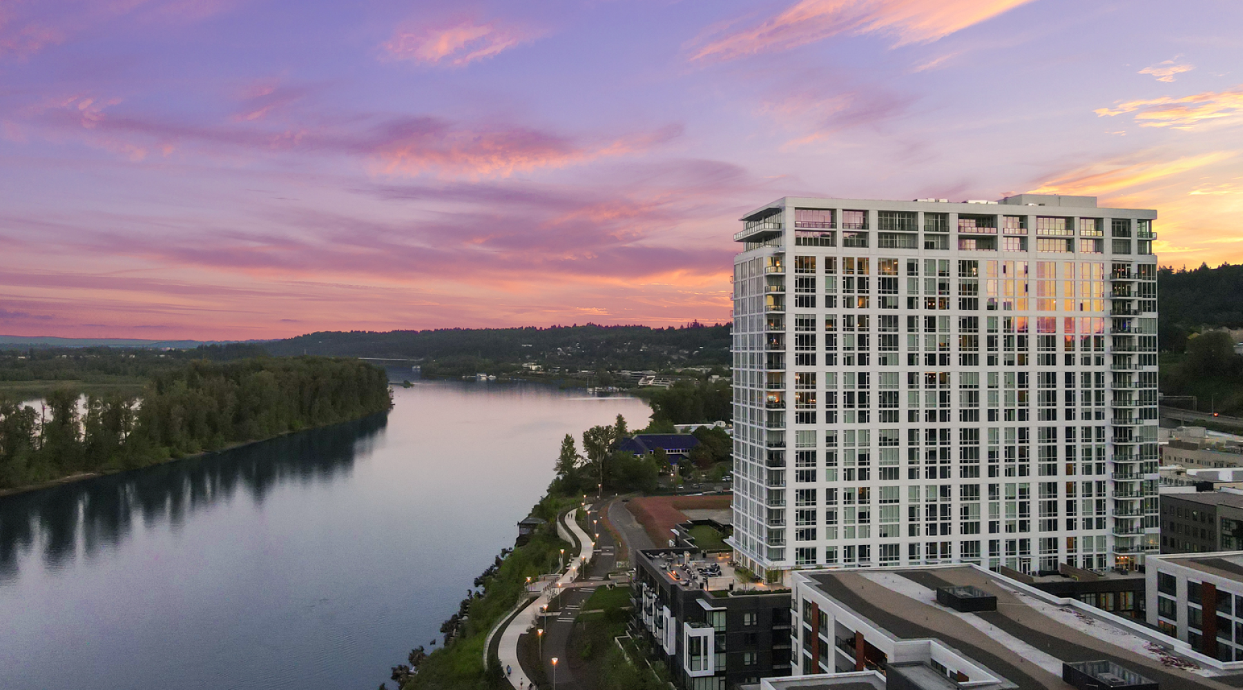 Exterior view of Willamette Tower luxury apartment building at dusk next to the Willamette River in Portland, OR